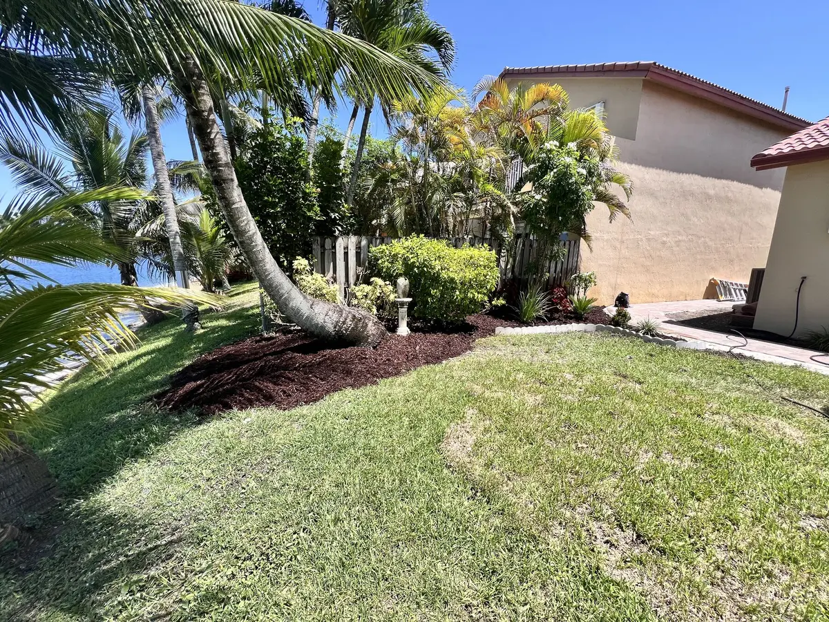 After: cleared, edged, and freshly mulched garden bed along the backyard fence
