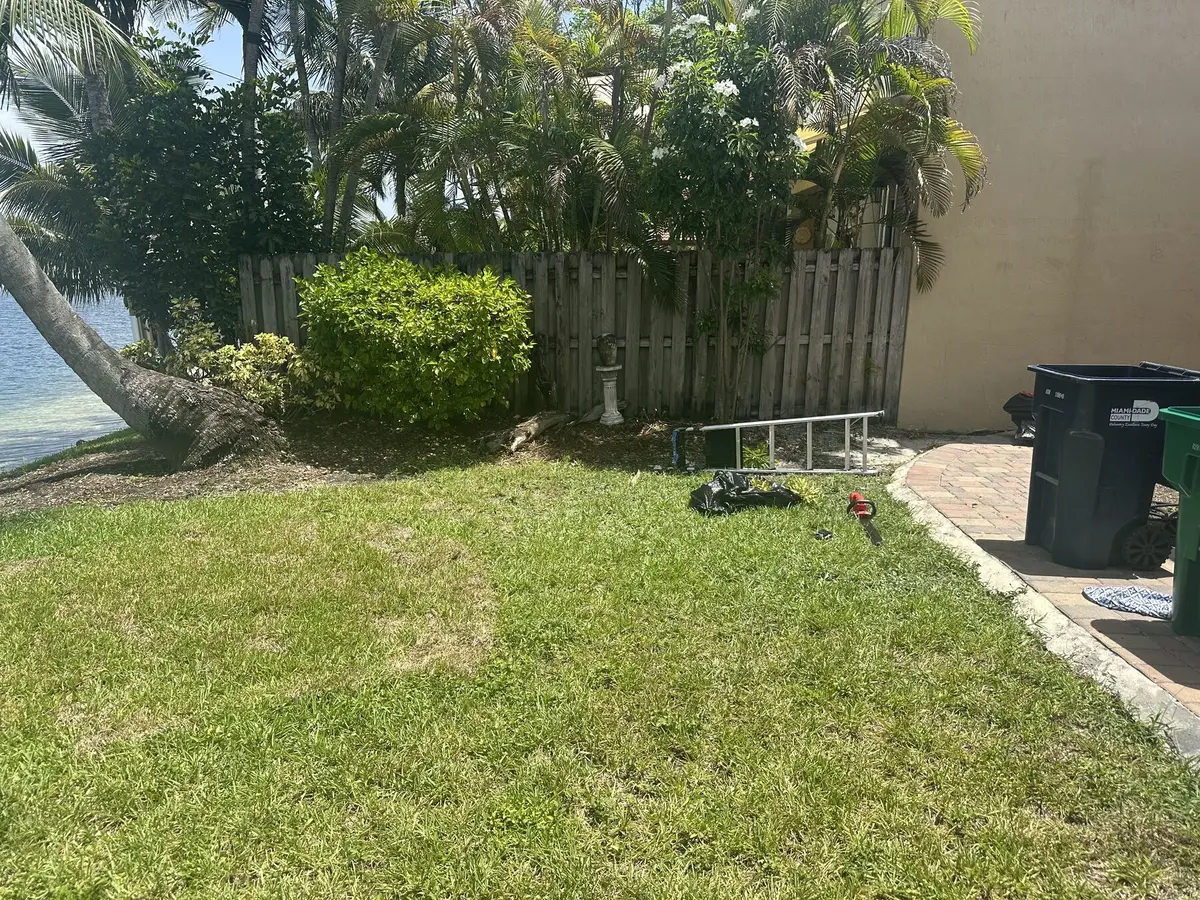 Before: overgrown garden bed with tools and debris along the backyard fence